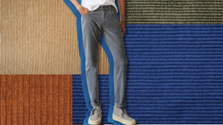 man from the waist down wearing grey corduroy pants, set against a background of a patchwork of different corduroy fabrics